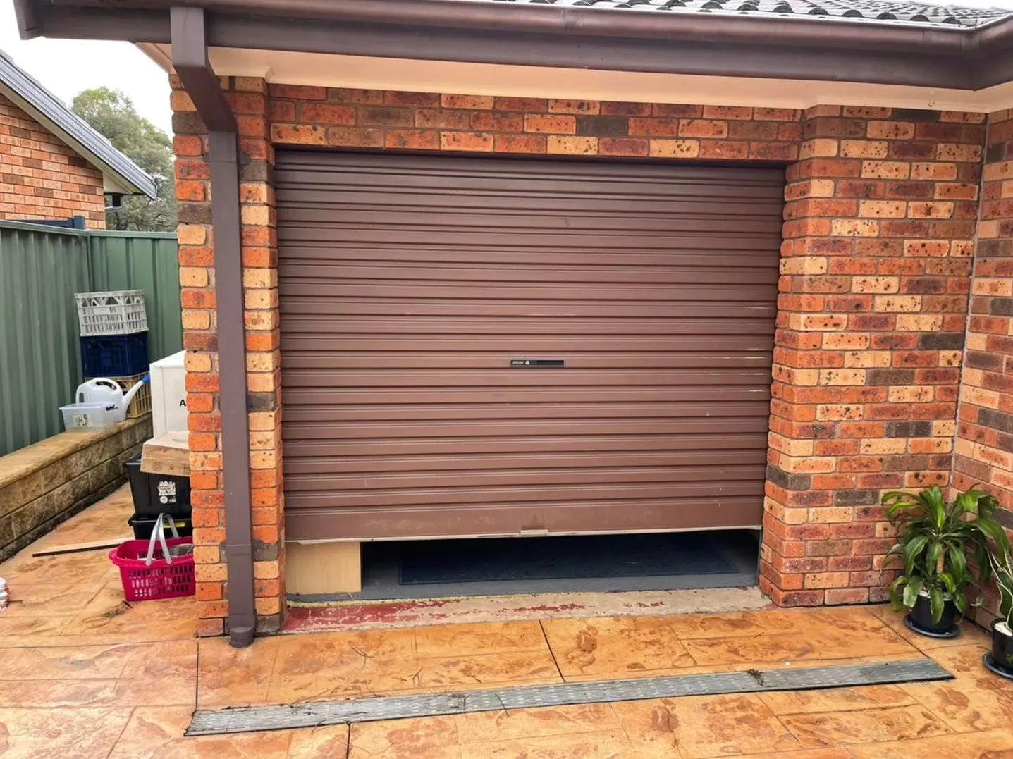 Brick wall with a brown roller door before the new doors