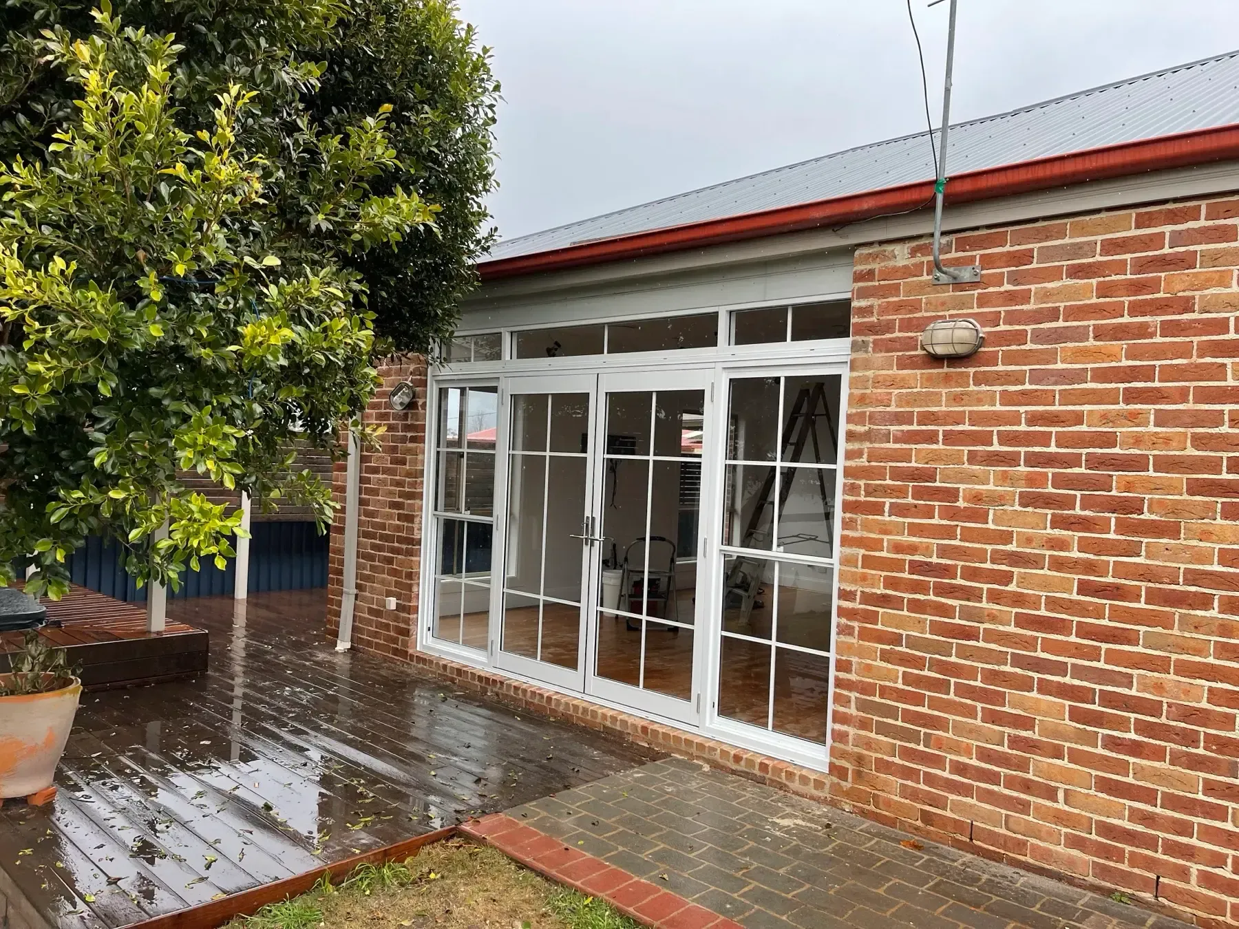 White French doors and grid windows in a brick extension beside a timber deck