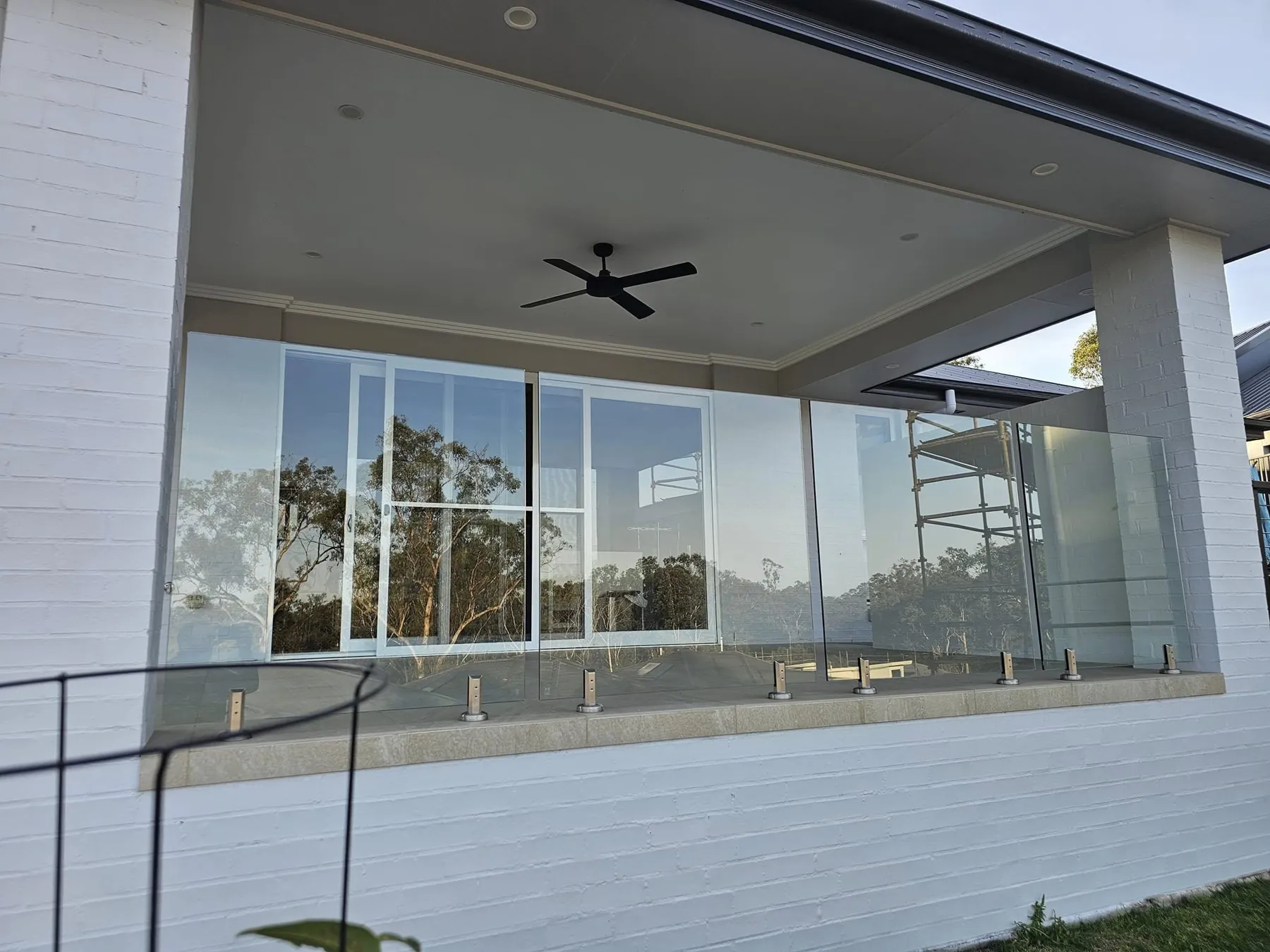 Covered patio enclosed with glass sliding windows and a glass balustrade
