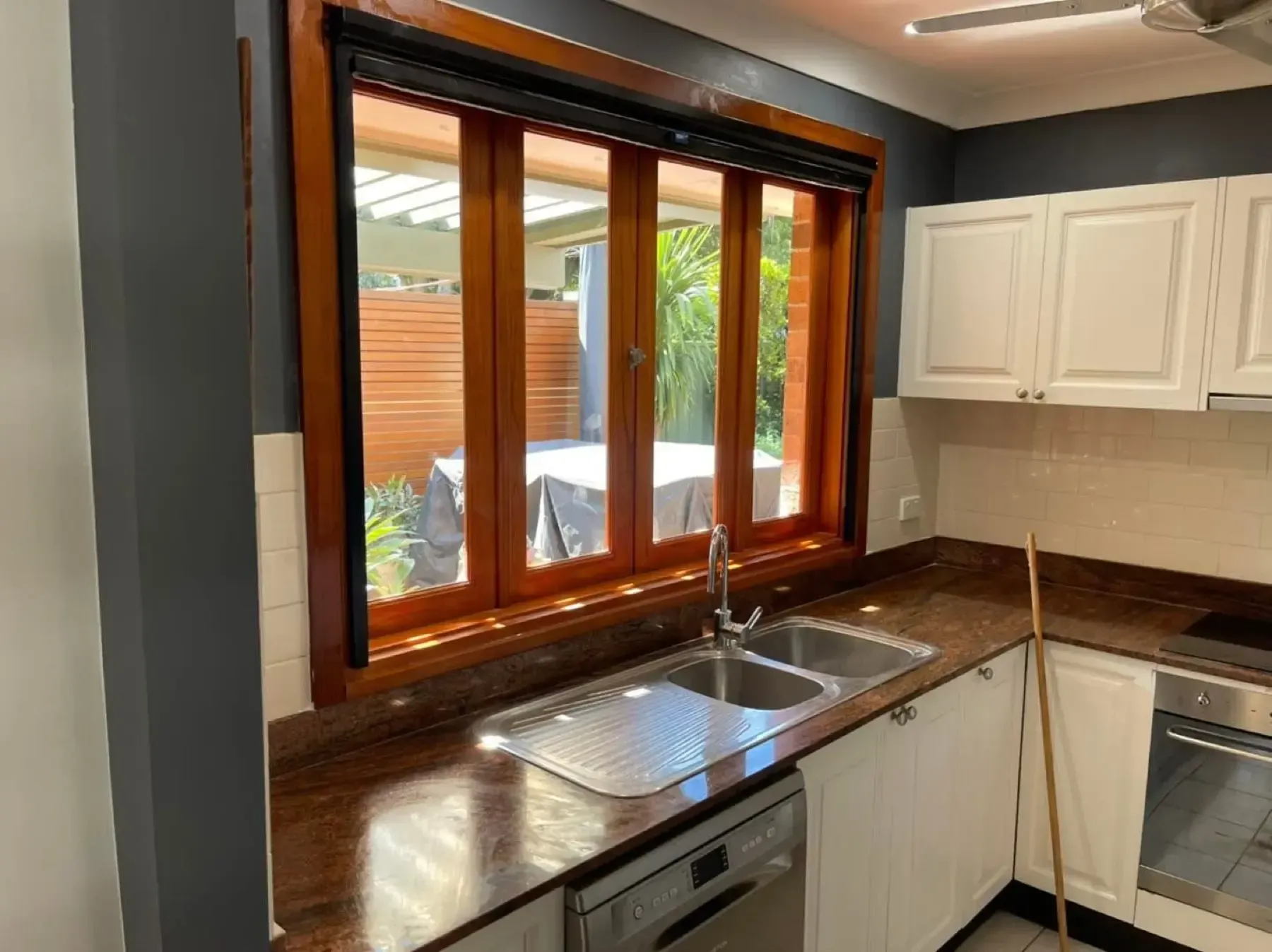 Timber-framed kitchen window above a sink with a covered patio visible outside