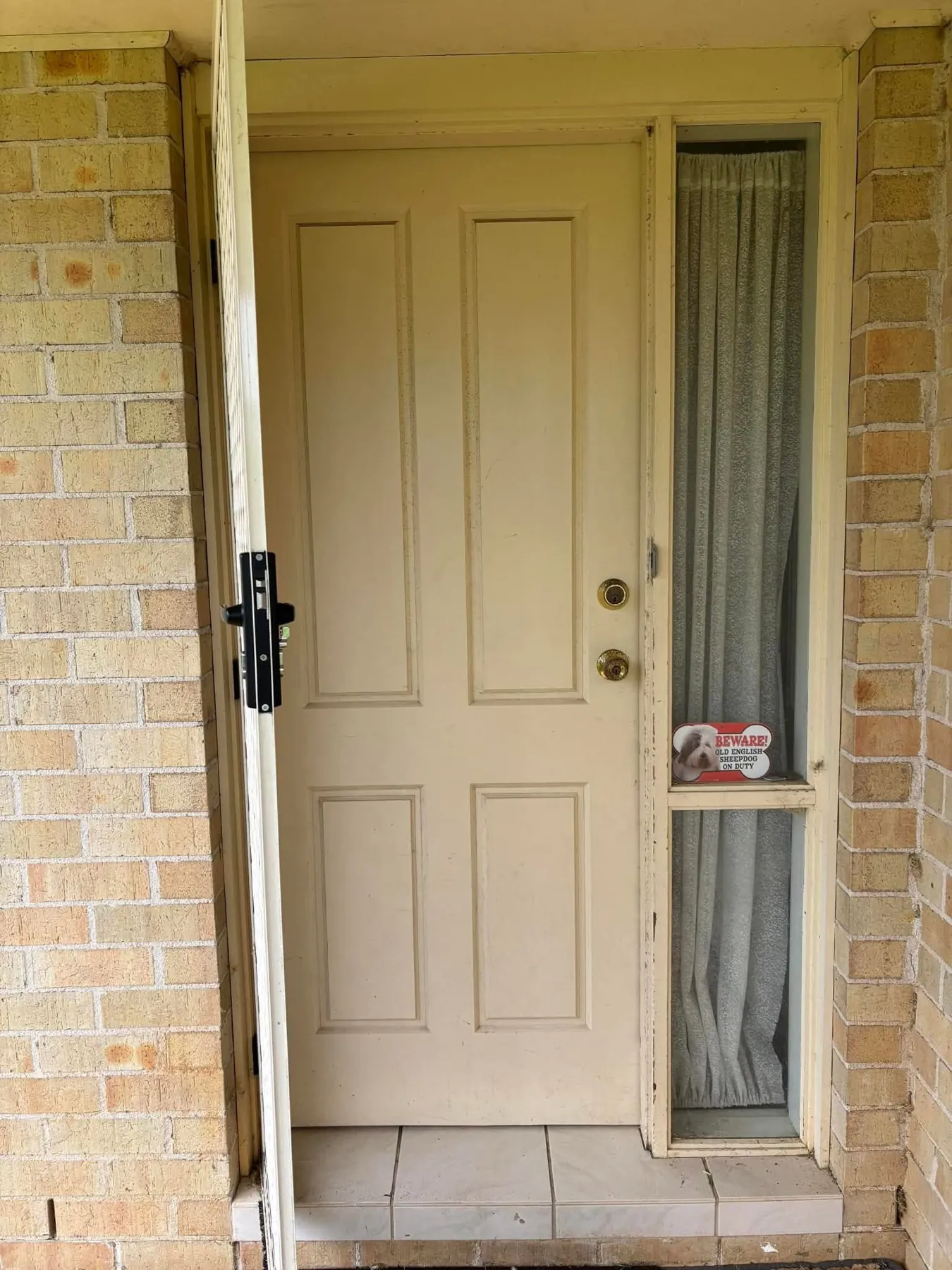 Painted timber panel door with a side light in a brick entry