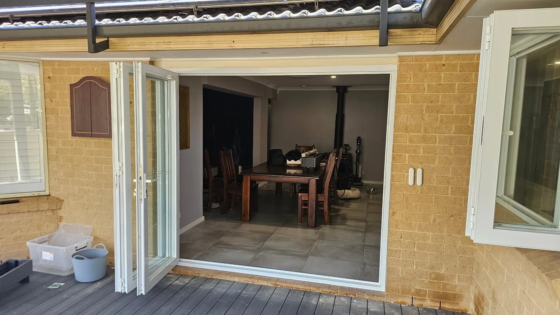 White bifold doors folded open from a deck into a dining room