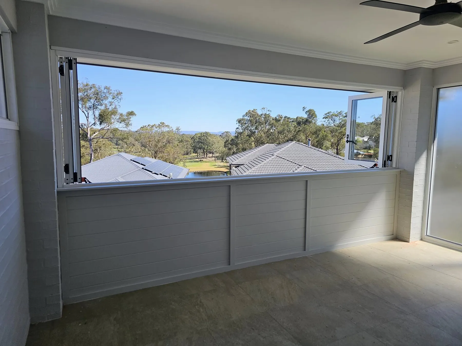 Wide aluminium servery window open from an enclosed alfresco room to a bushland view