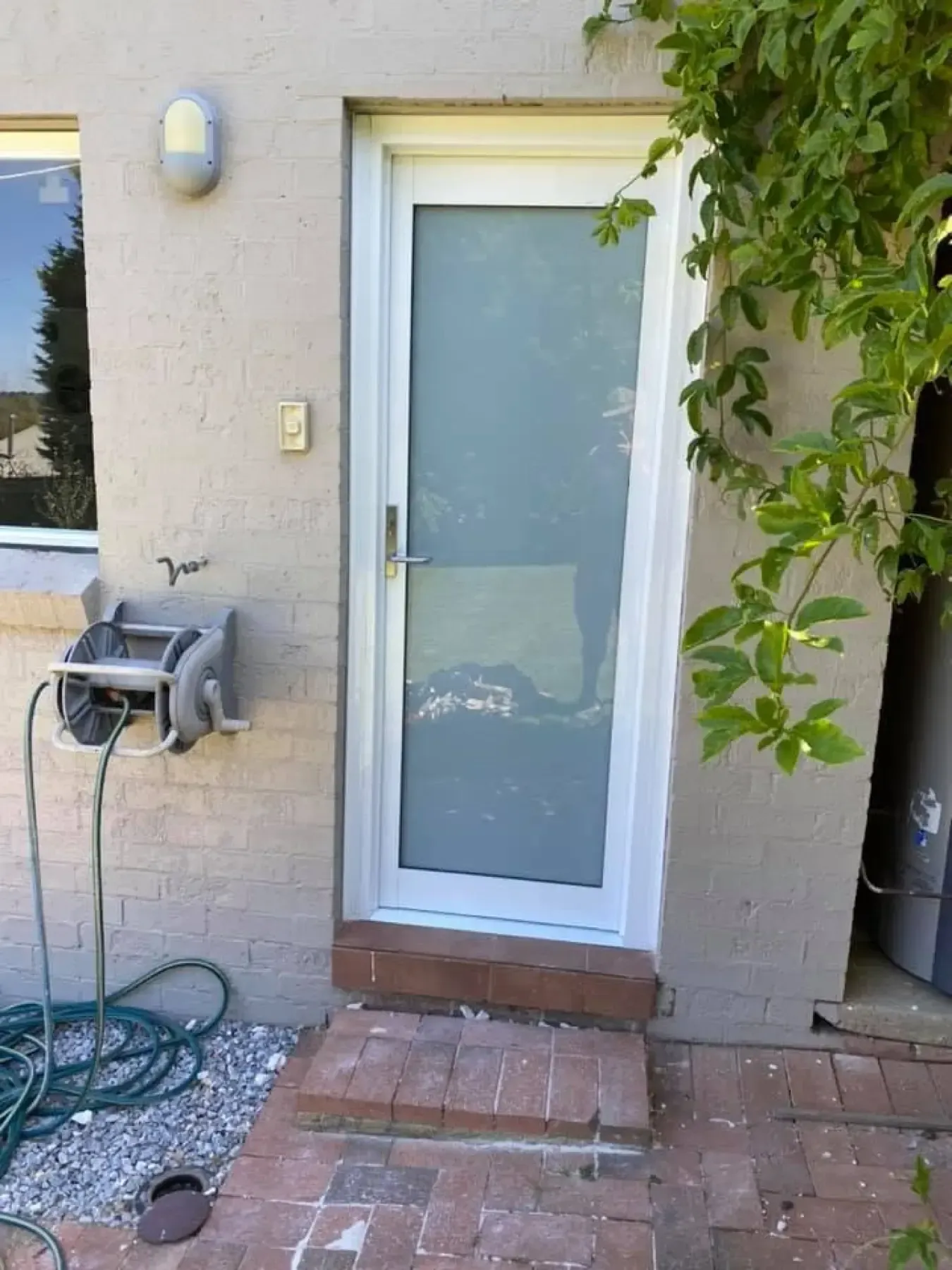 White aluminium door with frosted glass fitted at a rendered brick home