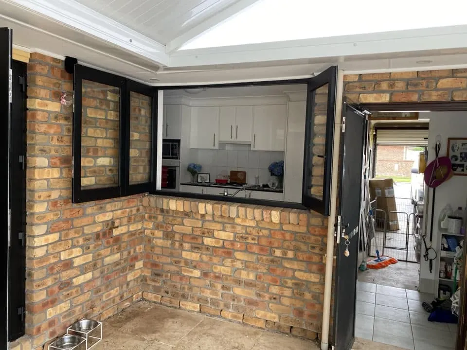Black-framed servery window and open doors in a brick alfresco wall