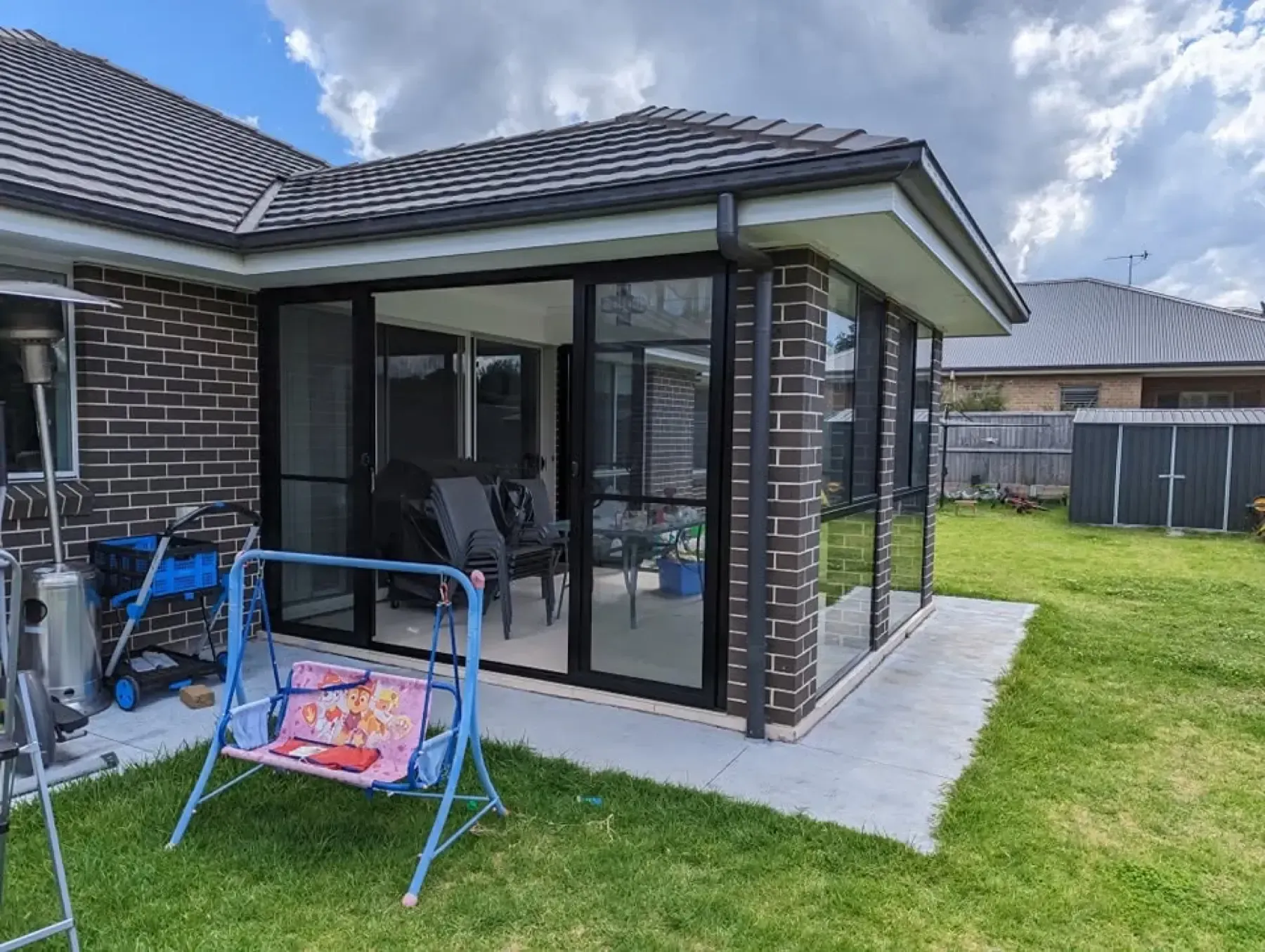 Brick home with a corner alfresco room enclosed by black aluminium sliding doors